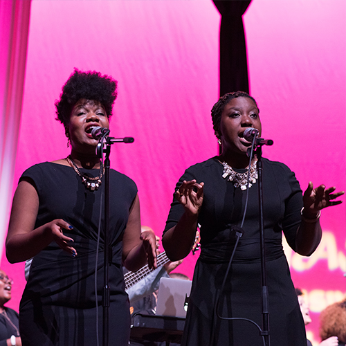 Two women singing onstage.