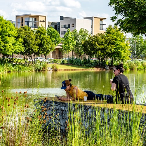 Two women lounging by the water in Railroad Park.