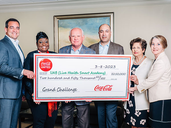 People holding large check showing donation. 