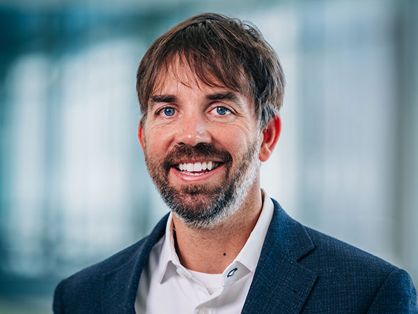 Headshot of a smiling, bearded man