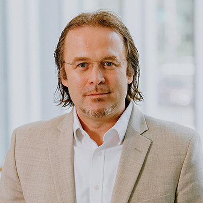 Patrick J. Murphy, Ph.D., wearing a tan blazer and white shirt with no tie.