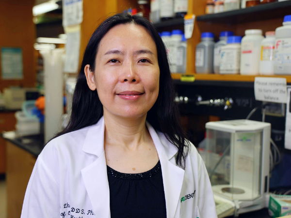 Image of woman with black hair in a white lab coat in a lab setting