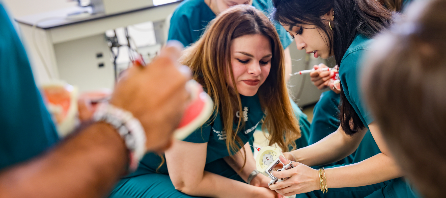Dental students looking at dental model among others in a class setting