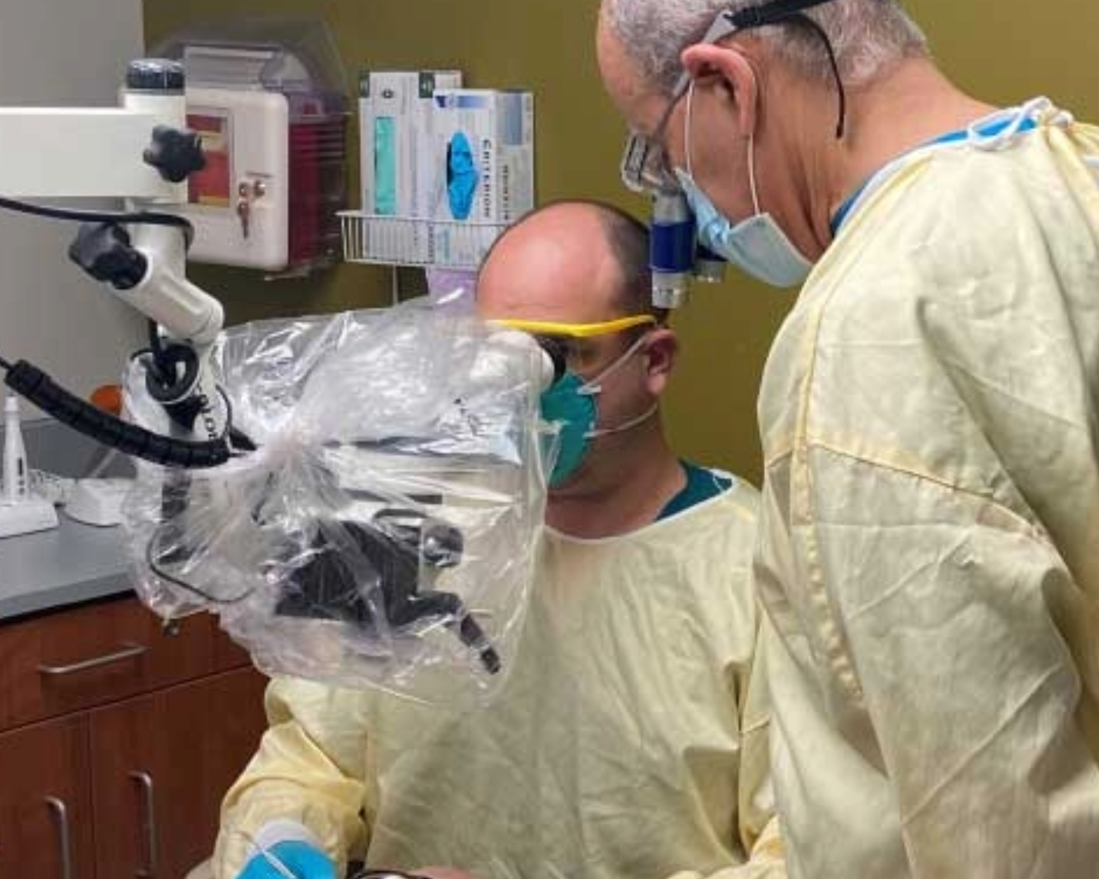 Dentist looking through magnifying device while working in a patient's mouth.