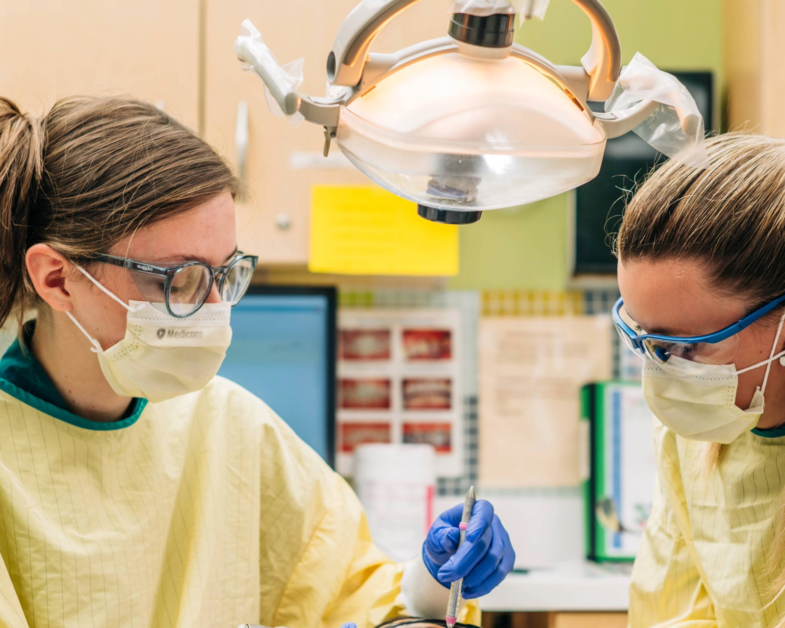 Two dentists examining a young girl's mouth.