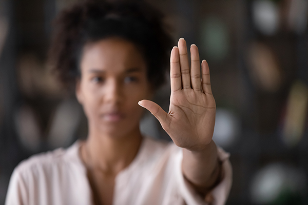 A woman in a pink shirt is pictured holding up her hand to indicate stop
