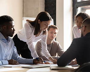 A group of business people gather around a conference table