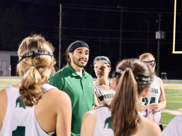 Chris Grijalba, DO, stands in a circle of lacrosse players