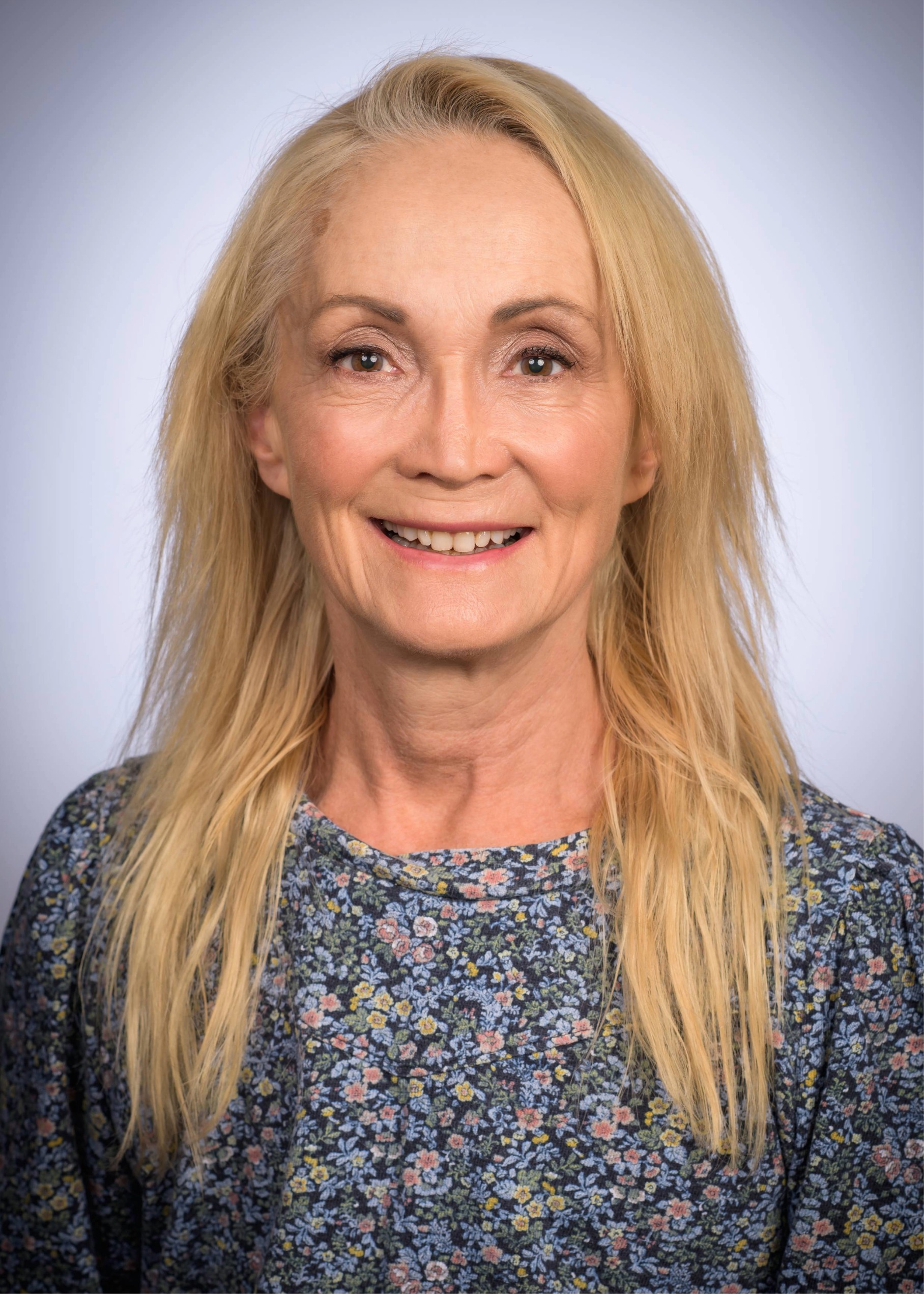 Maria Grant, MD, FARVO, wearing a floral-patterned top against a light blue background