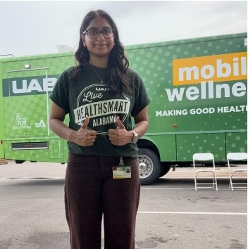 Dua Khan standing in front of the Live HealthSmart Alabama Mobile Wellness van