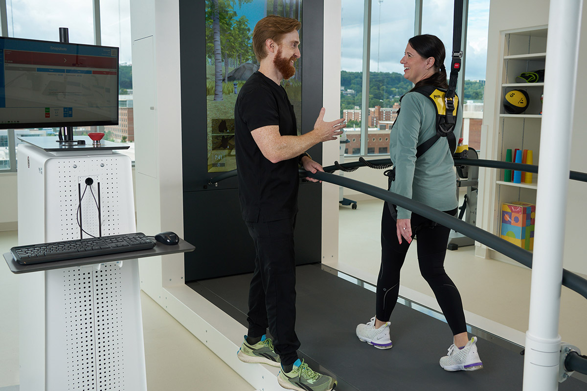 Rehabilitation patient walks on a treadmill using virtual reality to help regain mobility.