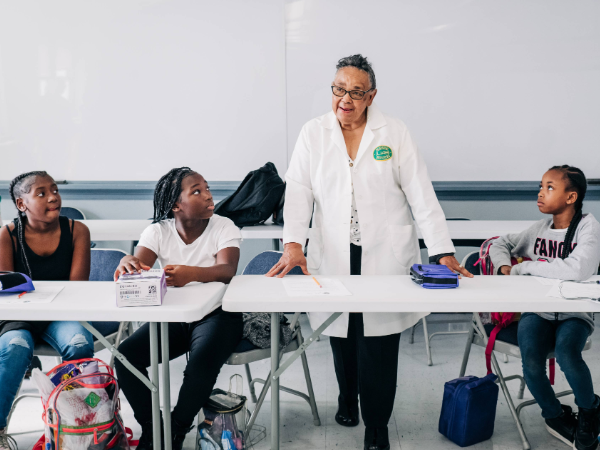Medical professional in a white coat with three students