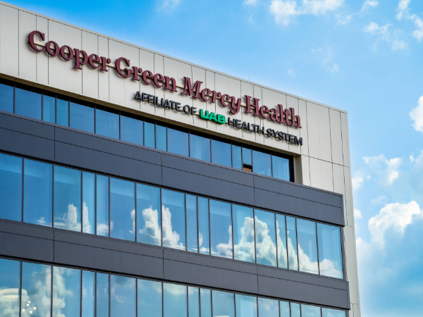 Cooper Green Mercy Health building exterior with its signage against a bright blue sky.