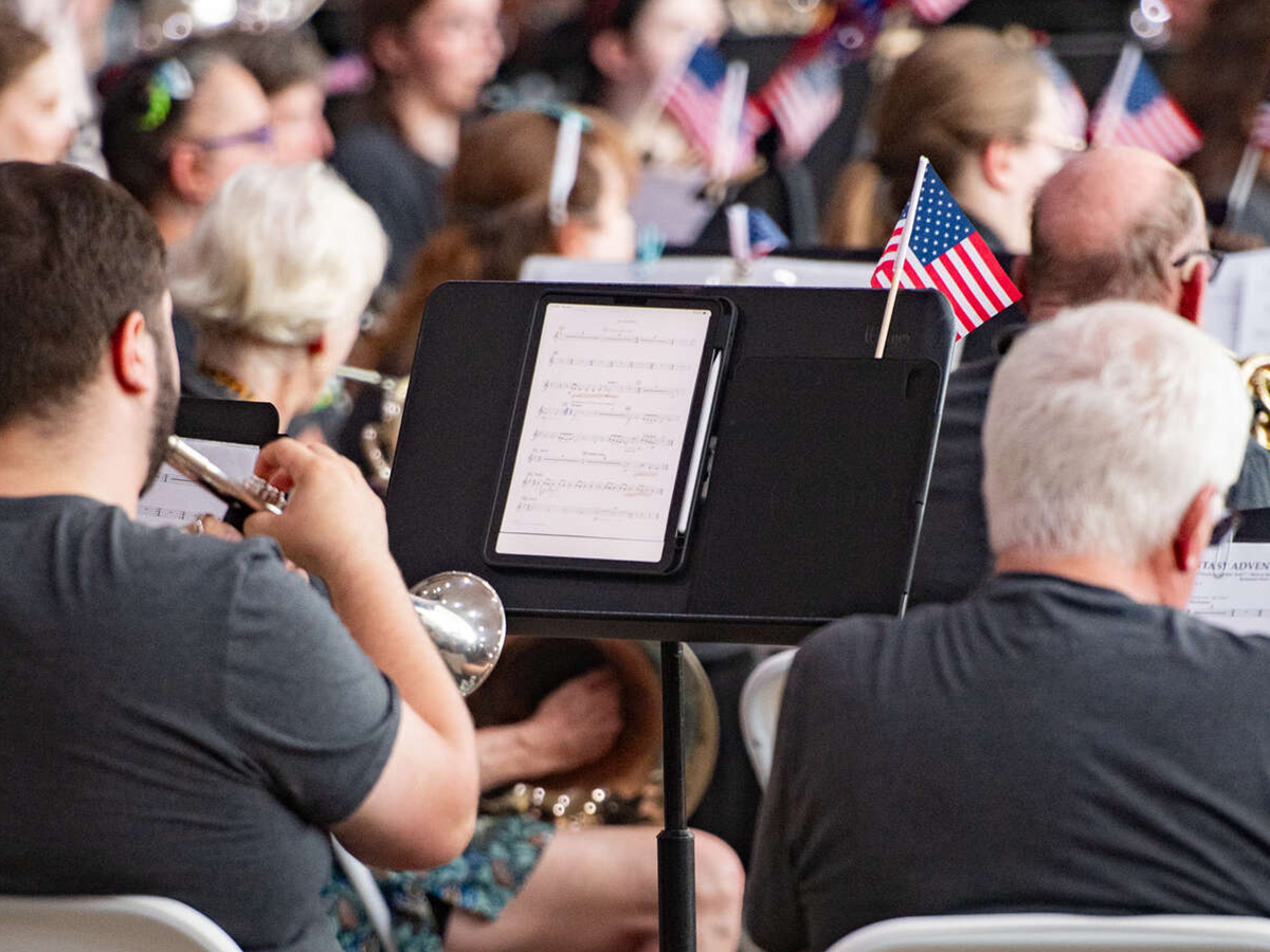 Musicians play their instruments while reading sheet music, with American flags adorning their music stands.