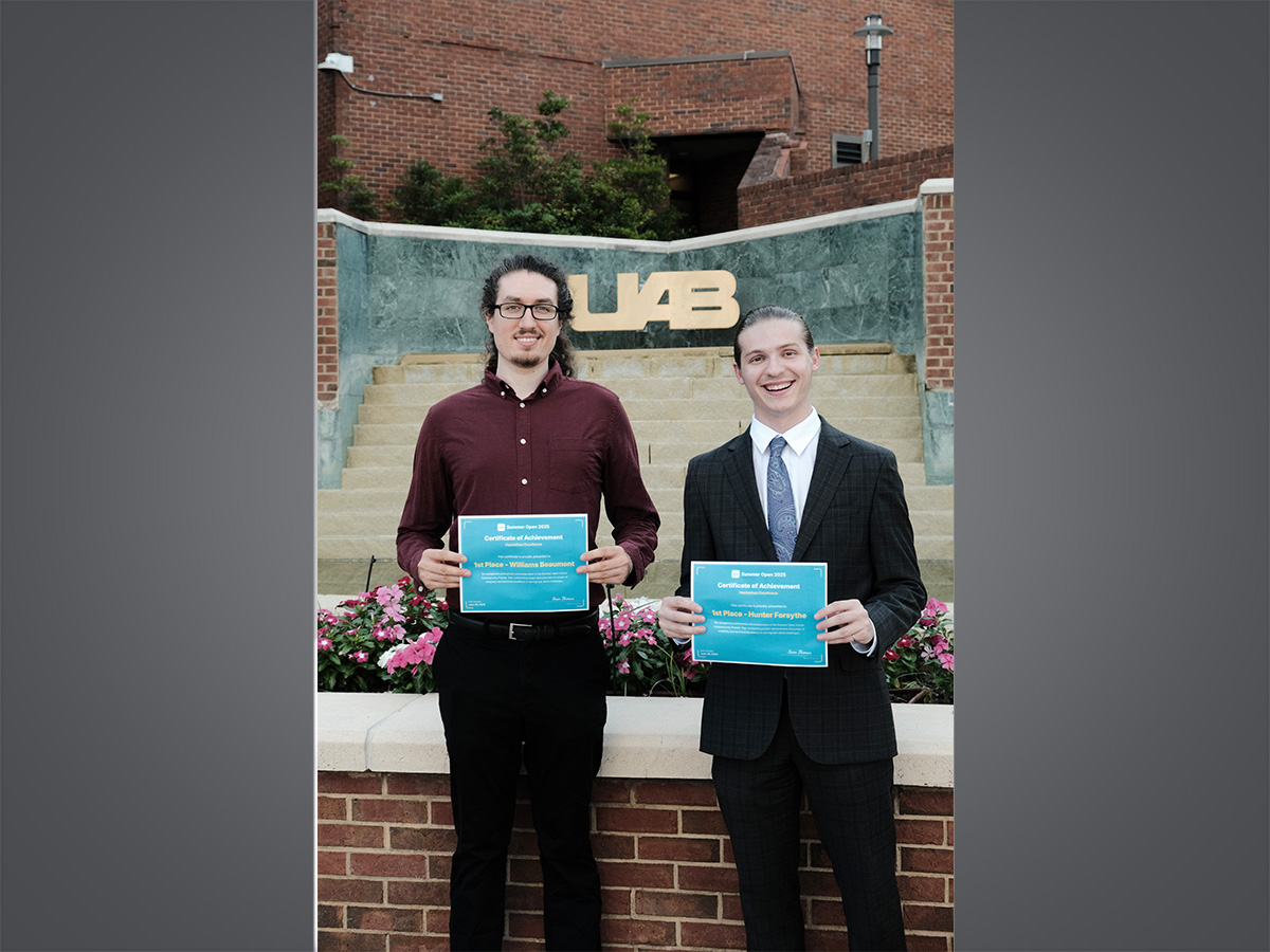 Two male students in front of a UAB sign