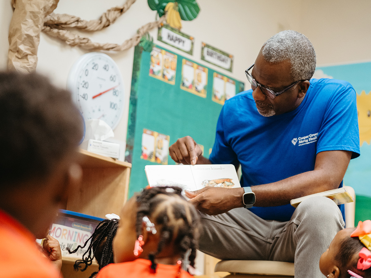 Raegan Durant, M.D., medical director of Cooper Green Mercy Health Services, reads book to group of children in classroom.