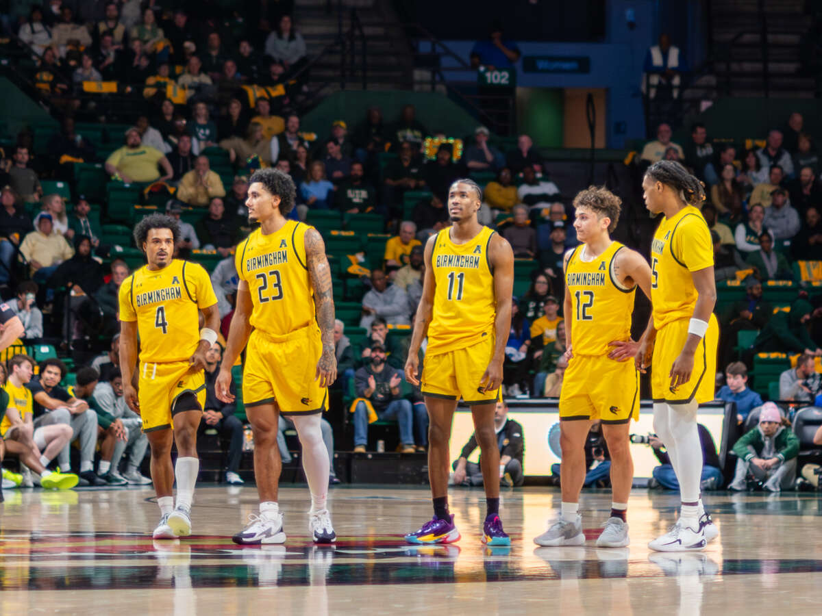 Several UAB Men's Basketball players are standing at center court prior to a game in Bartow Arena.