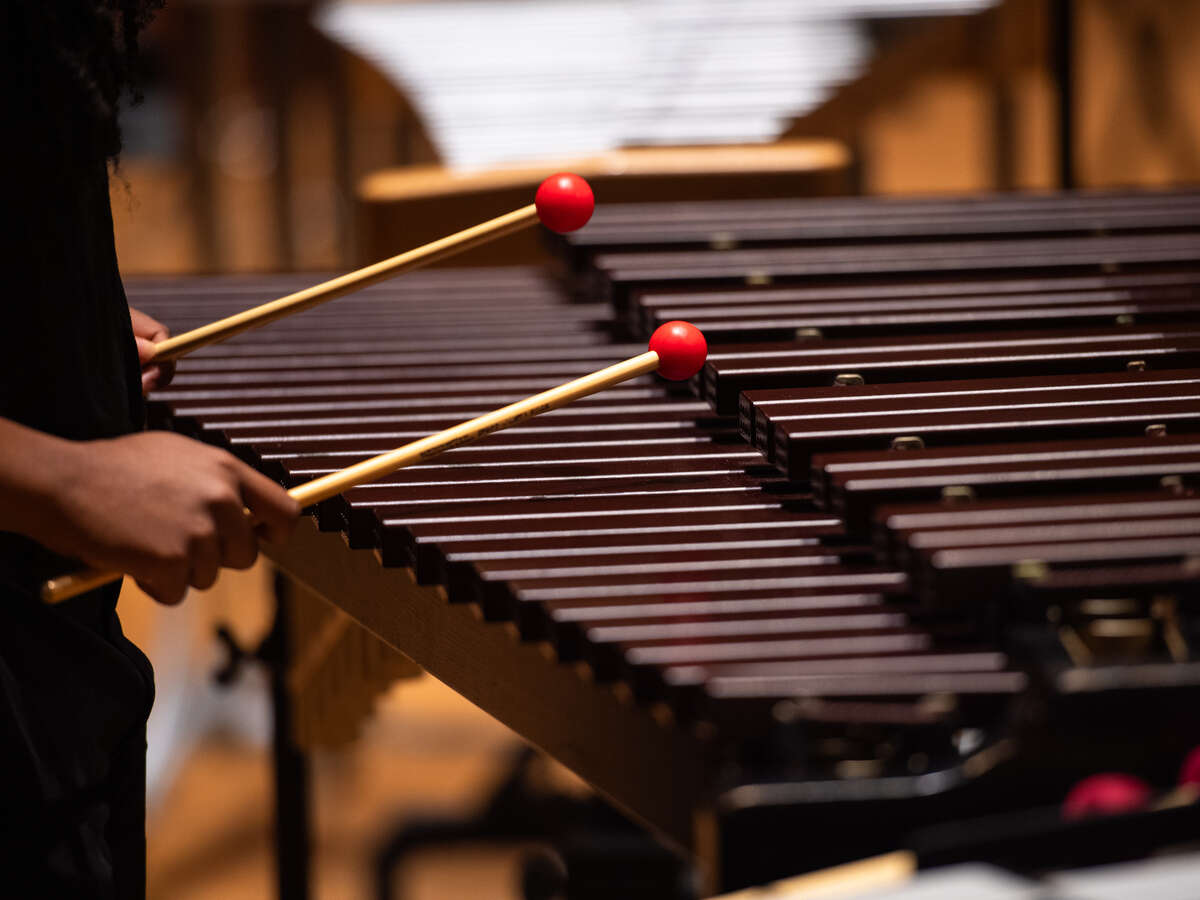 A person uses percussion mallets to play a marimba.