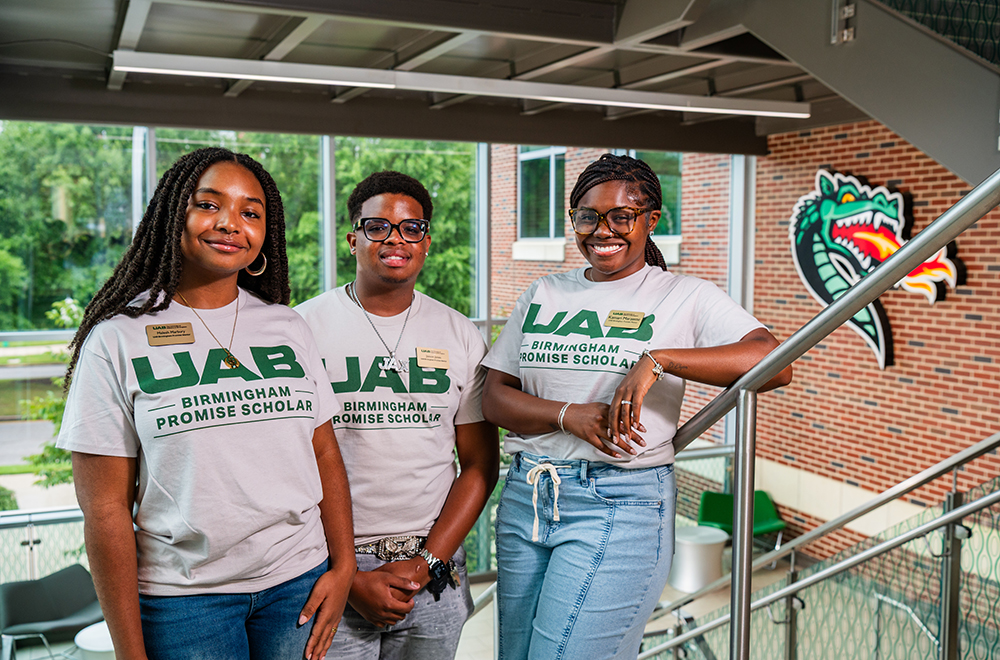 UAB Birmingham Promise student mentors Maleah Marbury, Jaxson Jones and Kamari Marzette stand on the staircase at the Hill Student Center on UAB's campus