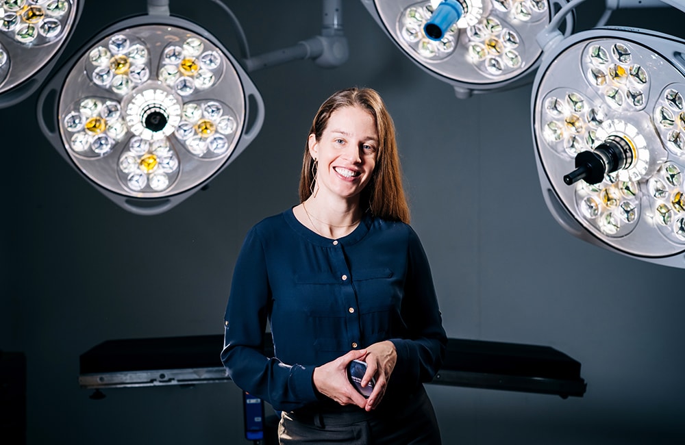 Kimberly Kopecky, M.D., holds a deck of cards from The Empathy Project, the game she created, while surrounded by surgical lights.