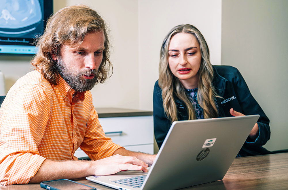 Pharmacist Edwards and clinician Schroeder look at data on a laptop