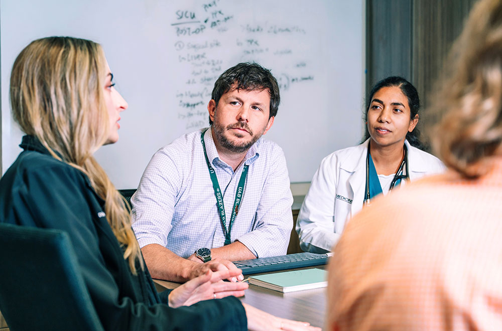 Four members of the Immunocompromised Infectious Diseases team discuss a patient case around a conference table