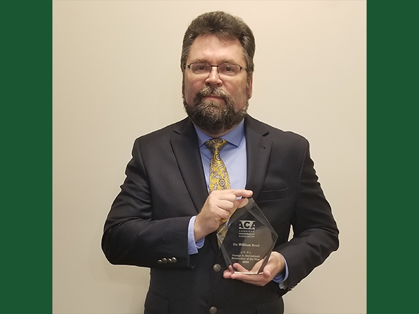 William Reed holding the researcher of the year award.