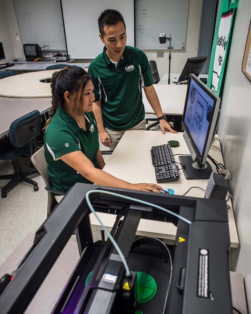 Two OT students practice with a 3D printer